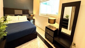 A bedroom with a bed, bedside tables, a lamp, a mirror, and a window. - ROOMIES HOSTEL Reforma - La Diana (Mexico City)