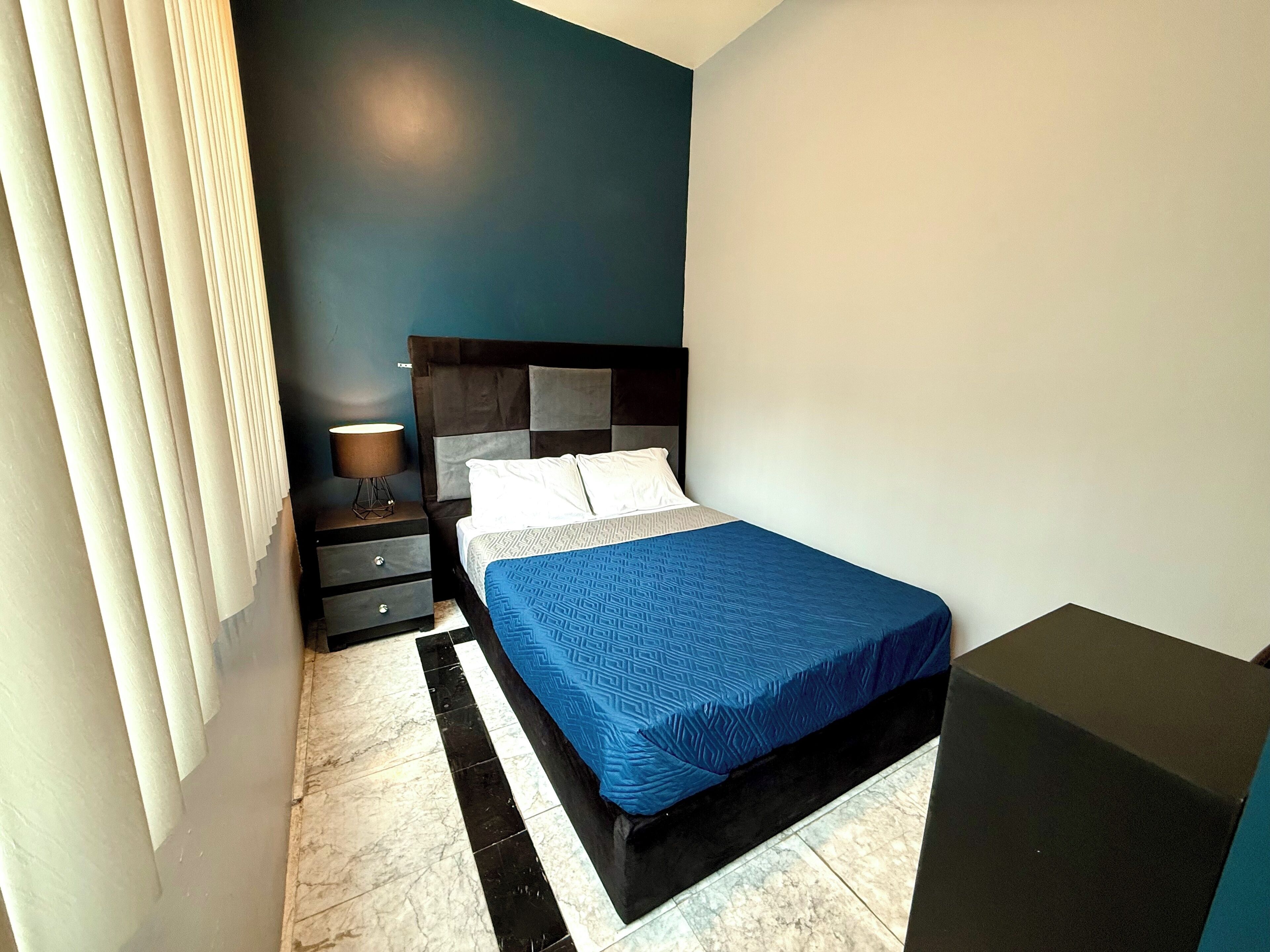 Une chambre à coucher avec un lit, une table de chevet, une lampe et une commode.