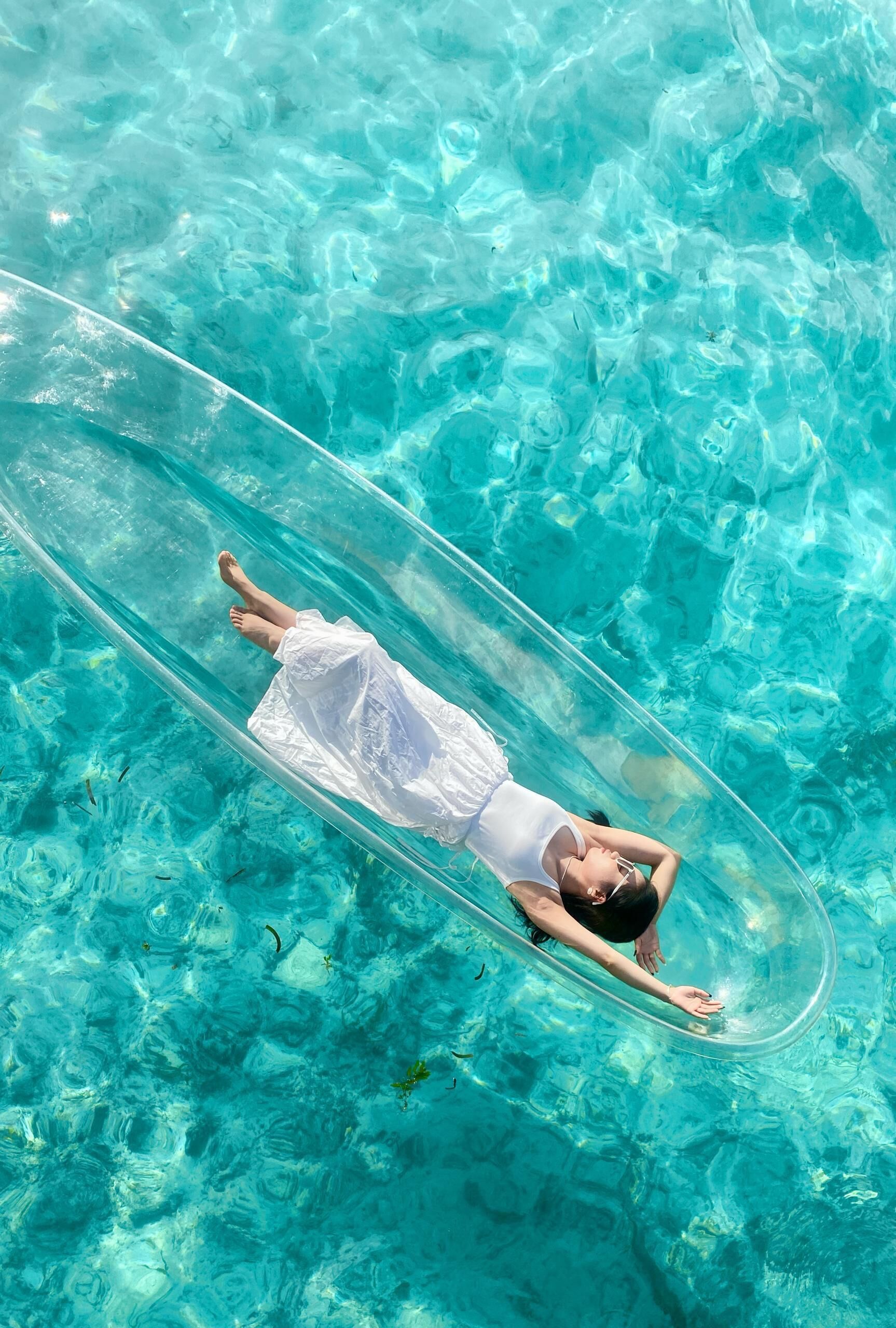Une personne flotte à l’intérieur d’un tube transparent dans une piscine à l’eau claire.
