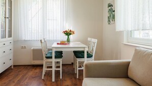 A room with a dining table, two chairs, a sofa, a cabinet, and a radiator. - Green House by Interhome (Balatonmariafurdo)