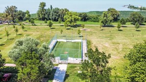 A sports field with a goalpost, surrounded by trees and a body of water in the background. - Green House by Interhome (Balatonmariafurdo)