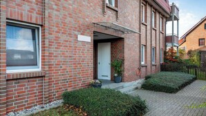 A red brick building with a white door and a small porch.
