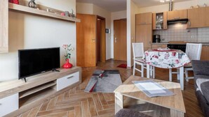 A compact living space with a TV, a dining table, and a kitchen area.