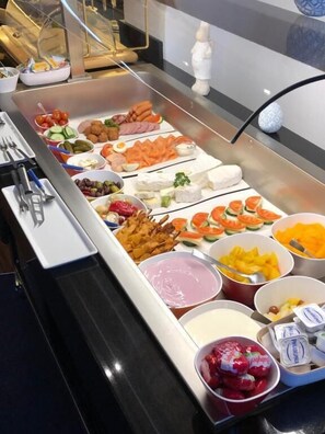 Un buffet proposant une variété d’aliments, notamment des fruits, des fromages et des sauces.