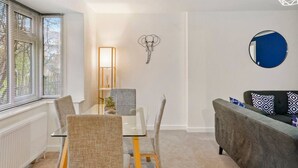 A modern living room with a dining table, chairs, a sofa, a wall-mounted mirror, and a decorative elephant head. - Barnet EN5 - Elegant 2Bed/1Bath Ground Floor Flat with FREE WiFi (Greater London)