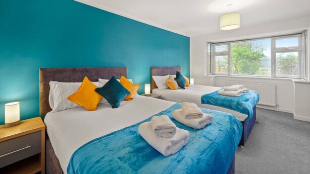 A hotel room with two beds, teal walls, and a large window. - Barnet EN5 - Elegant 2Bed/1Bath Ground Floor Flat with FREE WiFi (Greater London)