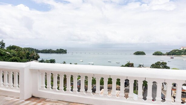 A balcony with a white railing overlooking a coastal view with boats and a bridge. - Villas Hillside apt 2 (Samaná)