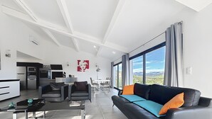 A modern living room with a sofa, chairs, a coffee table, and a kitchen in the background.