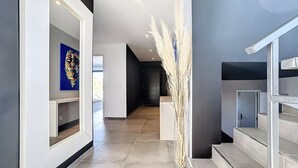 A modern hallway with a clear glass vase, a staircase, and a door leading to another room.