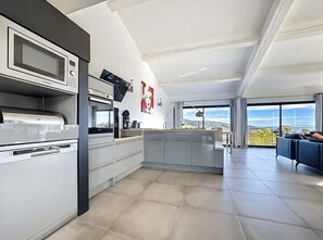 Uma cozinha moderna com micro-ondas embutido, cafeteira e vista para a cidade.