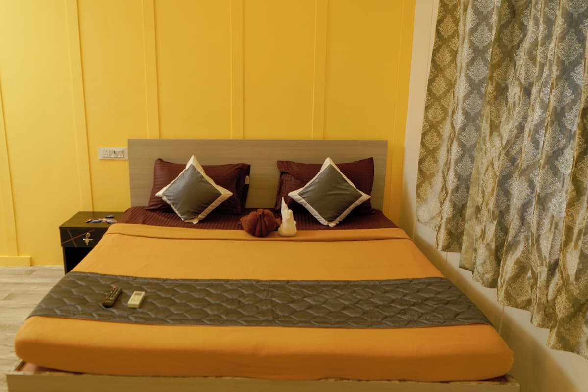 A bed with a headboard, two pillows, a blanket, and a bedside table with a remote control and a book.