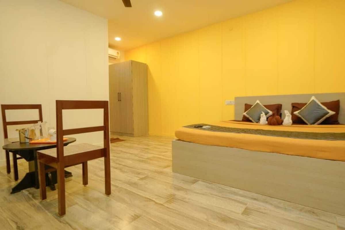 A bedroom with a bed, a chair, a small table, and a wardrobe.