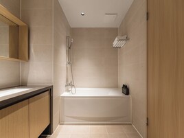 Un baño moderno con bañera, ducha y tocador con espejo.