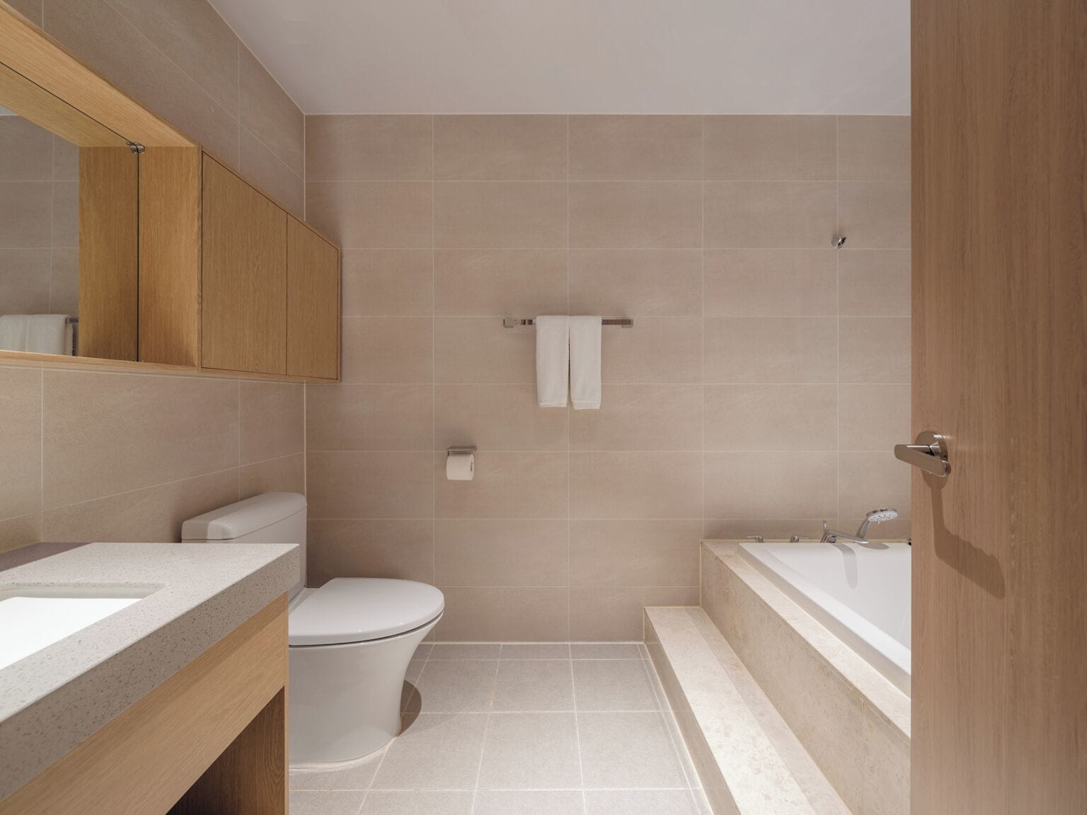 A modern bathroom with a toilet, sink, and bathtub.