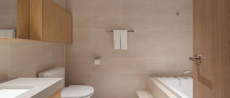 A modern bathroom with a toilet, sink, and bathtub.