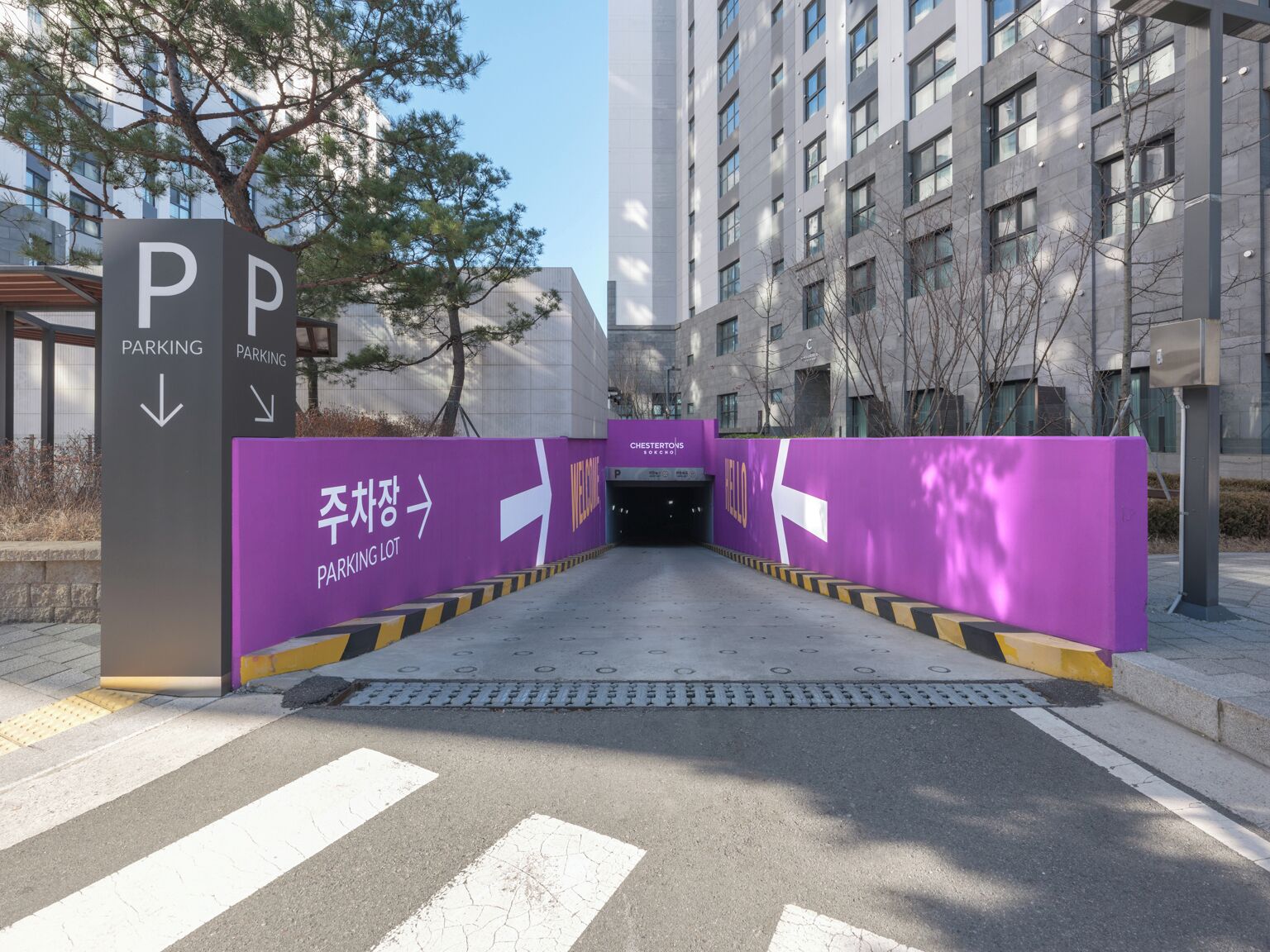 A modern building entrance with a parking lot sign and a welcome sign.