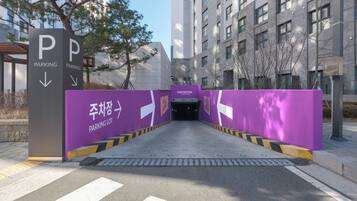 A modern building entrance with a parking lot sign and a welcome sign.