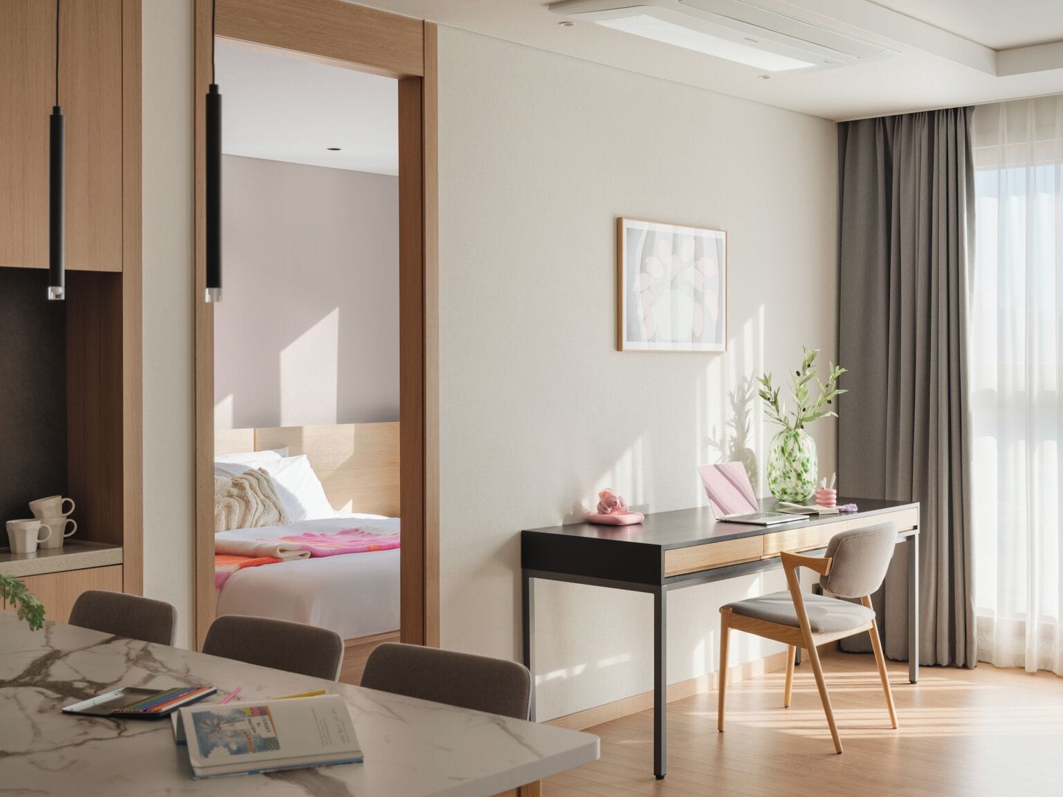 Une chambre d’hôtel moderne, équipée d’un lit, d’un bureau avec une chaise, d’une table à manger et d’une grande fenêtre avec des rideaux.