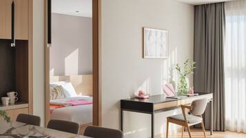 Une chambre d’hôtel moderne, équipée d’un lit, d’un bureau avec une chaise, d’une table à manger et d’une grande fenêtre avec des rideaux.