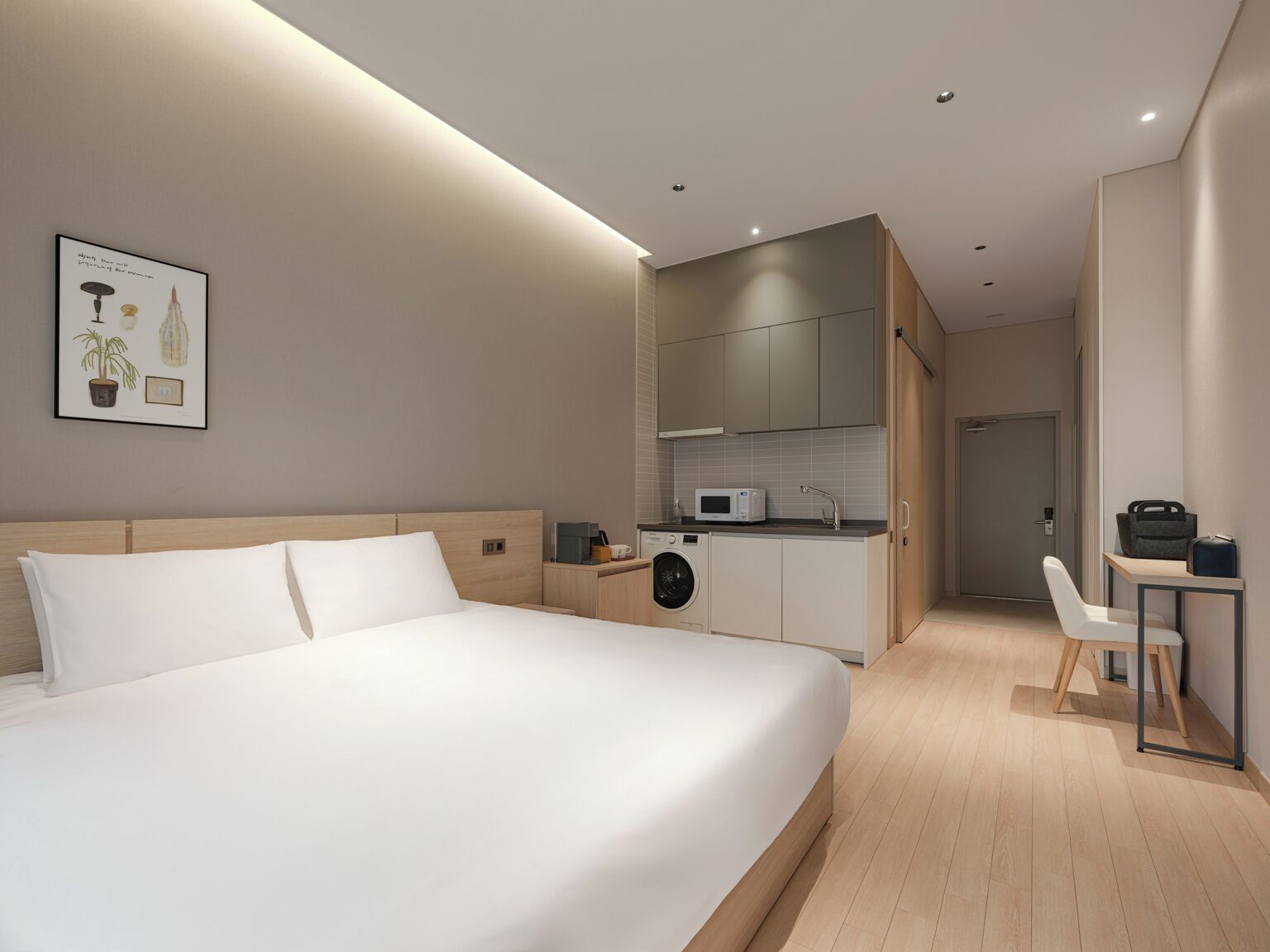 Habitación de hotel moderna con una cama grande, kitchenette, un pequeño comedor y baño.