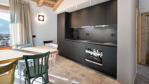 Une cuisine moderne dotée d’un four encastré, un coin repas avec une table et des chaises, et une vue sur l’extérieur.