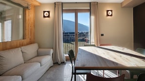 Una habitación con sofá, una mesa de comedor y vistas a la montaña.