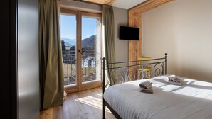 Un dormitorio con cama, cortinas, televisión y vistas a las montañas.