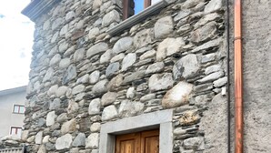 Un edificio de piedra con una puerta de madera, una ventana y una barandilla de metal.