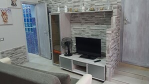 Una sala de estar con sofá, televisor, chimenea y puerta.