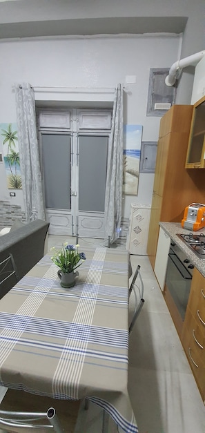 Une cuisine compacte avec une table à manger, une petite plante et une vue sur l’extérieur.