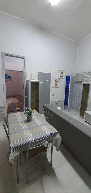 A compact kitchen with a dining area, a grey wardrobe, and a small table with a plant. - Apartment 'Centro Di Alcamo' with Balcony, Wi-Fi and Air Conditioning (Alcamo)