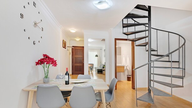 A dining area with a table, chairs, a clock, and a spiral staircase. - Apartment 'Olia' with Private Terrace, Balcony and Air Conditioning (Los Llanos)