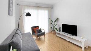 A modern living room with a sofa, a chair, a TV on a white stand, a floor lamp, and a potted plant. - Apartment 'Olia' with Private Terrace, Balcony and Air Conditioning (Los Llanos)