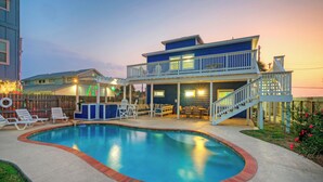 A two-story house with a swimming pool, outdoor seating, and a balcony. - Luxe Coastal Stay w/ Private Pool, Walk to Beach | Leave of Absence by AvantStay (Port Aransas)