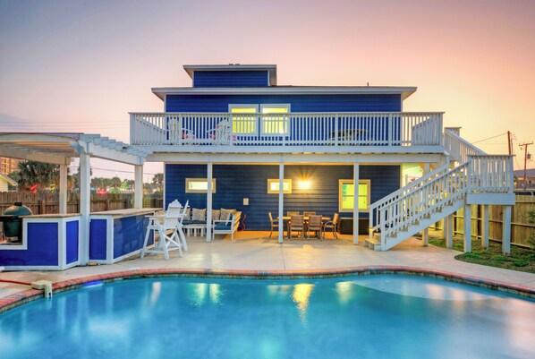 Une maison à deux étages avec une piscine, du mobilier d’extérieur et un patio couvert.