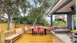 An outdoor patio with a wooden deck, a round table with chairs, a bench, and a sofa.