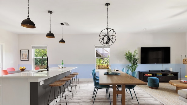 A modern kitchen with a central island, bar stools, and a dining area with a wooden table and chairs.