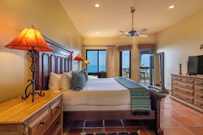 A hotel room with a bed, wooden dresser, TV, and a balcony with a view.