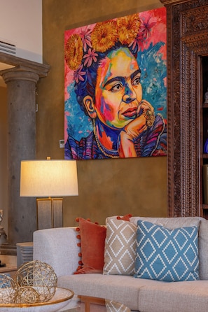 Un salon agrémenté d’un tableau coloré, d’une lampe et d’un canapé avec des coussins à motifs.