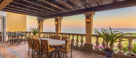 An outdoor patio with a table and chairs, overlooking a body of water.