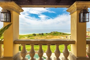Un balcon avec vue sur la mer et une colline verdoyante.