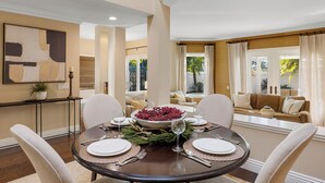 Un coin repas avec une table ronde, des chaises et une décoration centrale composée de baies rouges et de verdure.