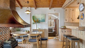 A cozy kitchen with wooden cabinets, a large stove, and a dining area with a table and chairs. - California Dreamin by AvantStay | Private Pool + Fire Pit | Near the Beach (Carlsbad)