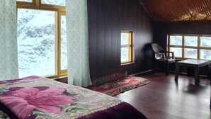 A room with a large bed, a chair, a small table, and a window with a view of trees. - Charming bed & breakfast with WiFi in Raling Khangsar (Raling)