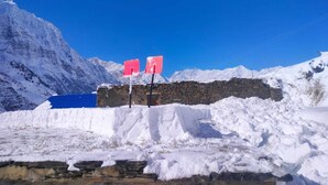 A snow-covered mountain with a stone wall and two red signs. - Charming bed & breakfast with WiFi in Raling Khangsar (Raling)