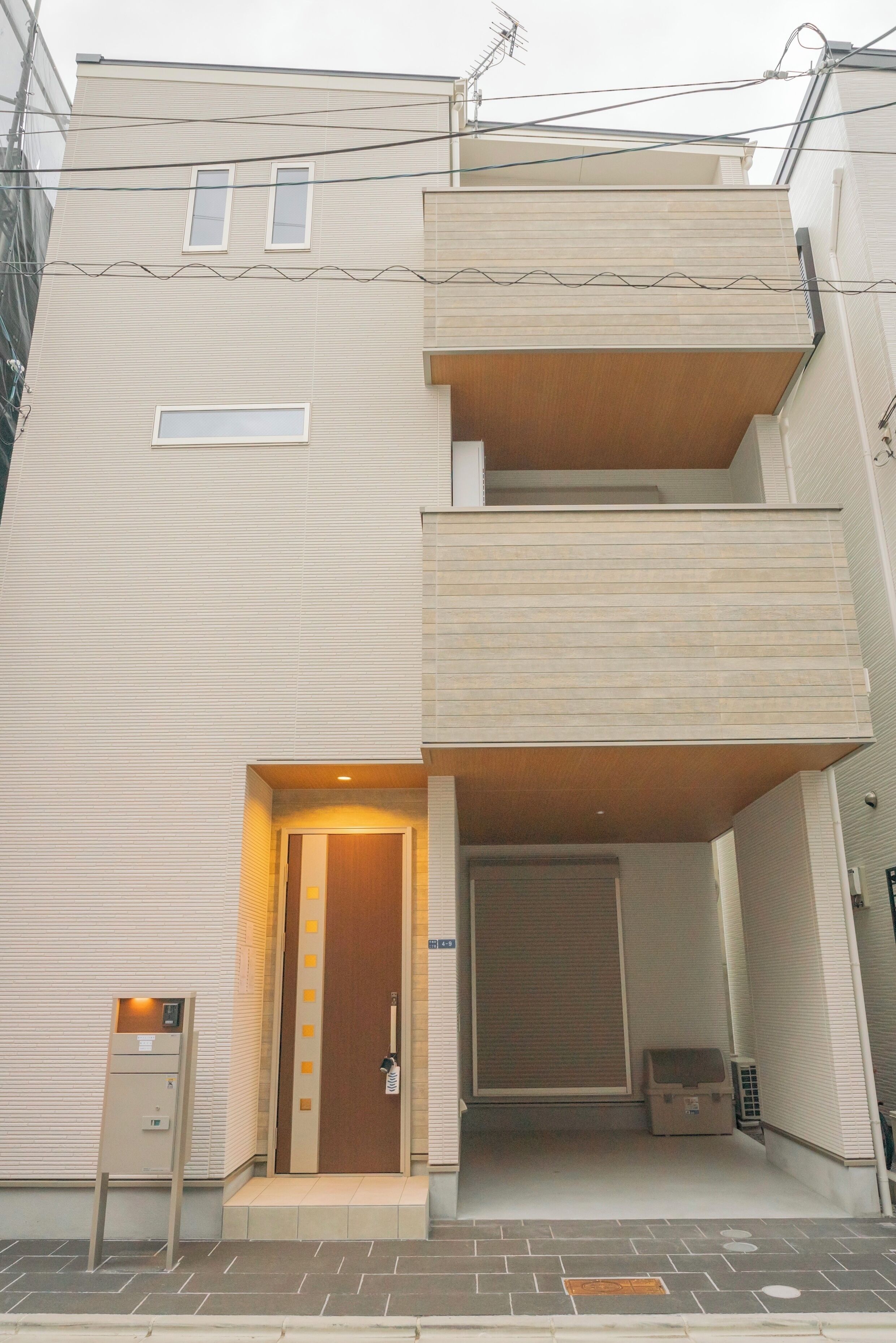 Un edificio de varios pisos con fachada plana, una puerta de madera y un pequeño espacio al aire libre con un banco.