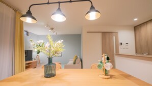 A dining area with a wooden table, a vase with flowers, and a coffee machine.