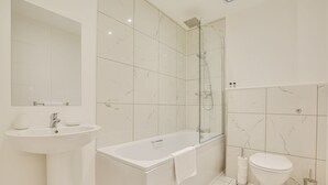A modern bathroom with a bathtub, toilet, and sink. - Host Stay Canalside Lofts Apartment (Burnley)