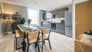 A modern kitchen with grey cabinets, a built-in oven, and a large refrigerator.