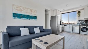 A modern living room with a grey sofa, a wooden coffee table, and a kitchen in the background. - Casa Martin - Sea Views (Torremolinos)